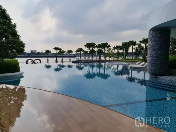 公寓 出售在Yan Nawa, Bangkok - 公寓的江畔无边泳池，配有躺椅与棕榈景观。