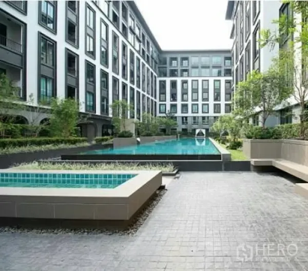 Condominium for rent in Pathum Wan, Bangkok - Modern low-rise condominium courtyard with a long swimming pool, greenery and seating areas.