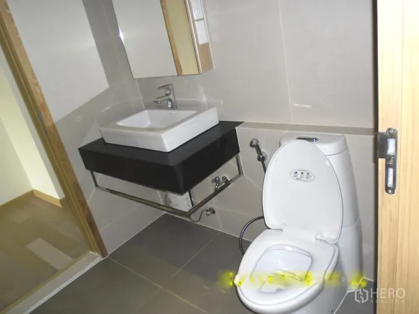 Condominium for rent or sale in Watthana, Bangkok - Clean tiled bathroom with square vanity sink, mirror, and white toilet in a Bangkok condominium.