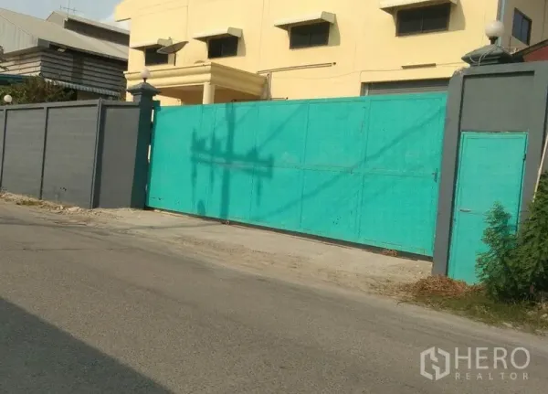 工厂 出租在Bang Phli, Samut Prakan - 工厂临街入口，高墙与宽大的绿色滑动大门。