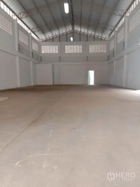 Factory for rent in Lat Lum Kaeo, Pathum Thani - Spacious high-ceiling factory interior with concrete floor, steel truss roof, ventilation blocks and bright lighting.