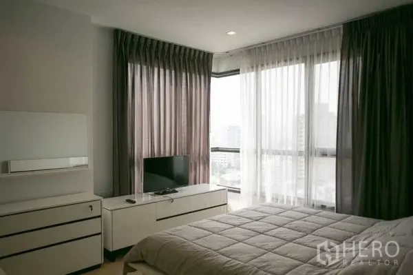 Condominium for rent in Watthana, Bangkok - Corner bedroom with floor-to-ceiling windows displaying Bangkok city views.