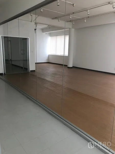 Office Space for rent in Bang Rak, Bangkok - Full-height mirrored glass partition reflecting a large office area with blinds.