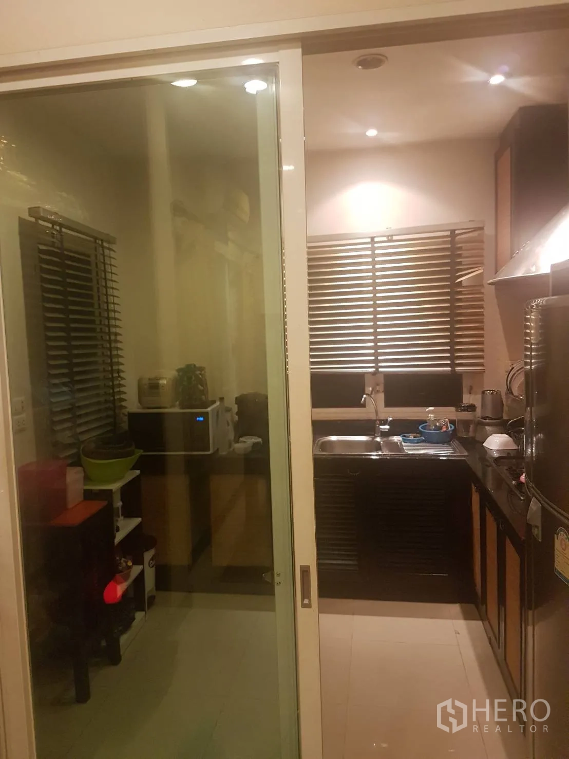 Detached House for sale in Lat Krabang, Bangkok - Enclosed kitchen behind a sliding glass door with stainless sink, range hood and cabinets.