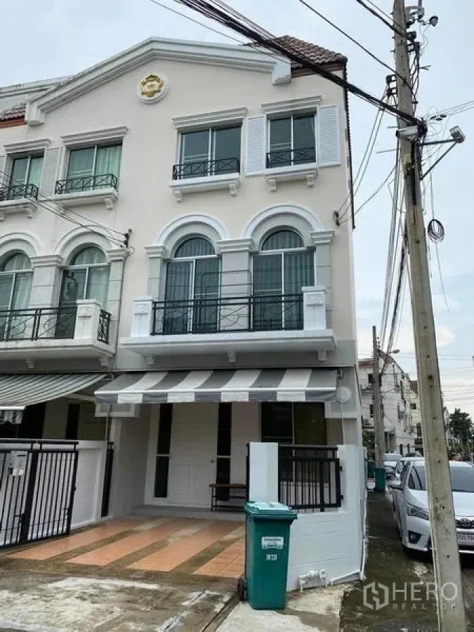 Townhouse for rent in Lat Phrao, Bangkok - Three-storey townhouse exterior with arched windows, balconies and gated parking in Lat Phrao, Bangkok.