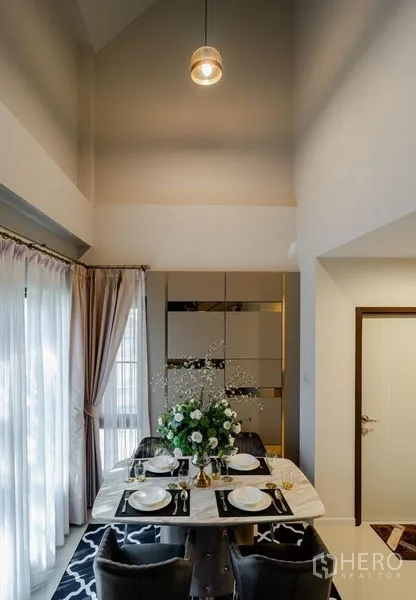 Detached House for sale in Lam Luk Ka, Pathum Thani - Dining room with tall windows, soft drapes, and a marble table set for four.