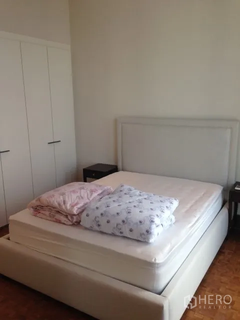 Condominium for rent or sale in Bang Rak, Bangkok - Second bedroom with upholstered bed and full-height wardrobes in neutral tones.