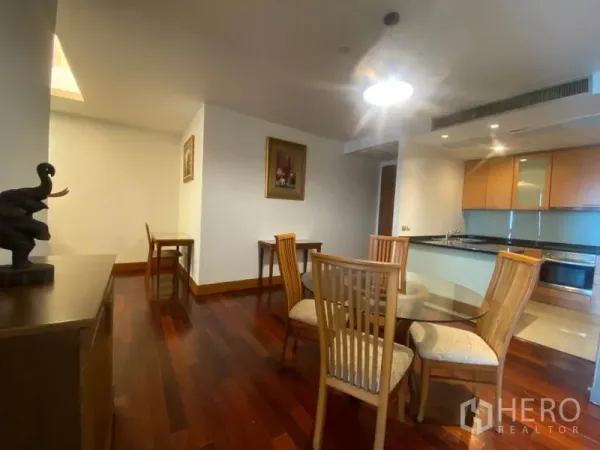 公寓 出租在Sathon, Bangkok - 餐区与厨房相连，圆形玻璃餐桌和木椅，布局开阔。