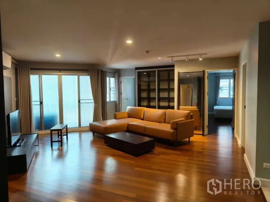 Condominium for sale in Yan Nawa, Bangkok - Bright living room with sliding balcony doors and a large sectional sofa.