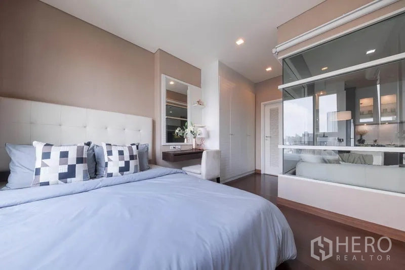 Condominium for rent in Watthana, Bangkok - Bedroom with glass partition to living room and built-in wardrobes.
