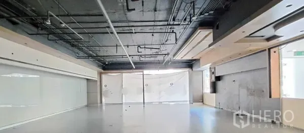 零售空间 出租 - 开放式零售室内，黑色外露天花与管线、浅色地面、整面落地玻璃门面，待二次装修。