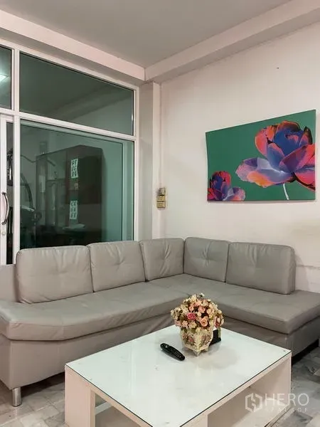 Home Office for rent in Ratchathewi, Bangkok - Bright living area with L-shaped gray sofa, white coffee table and sliding glass doors.