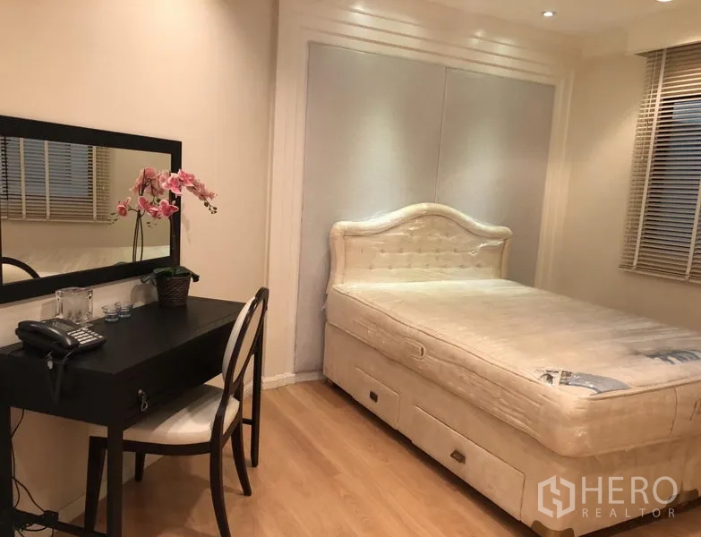 Condominium for rent or sale in Sathon, Bangkok - Second bedroom with padded bed base, dressing desk and large wall mirror.