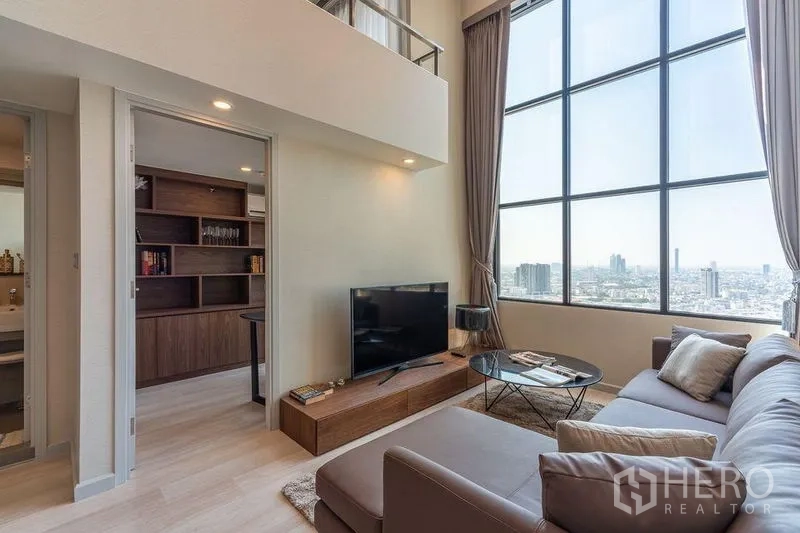 公寓 出租在Sathon, Bangkok - 客厅配电视柜与地毯，旁连书房，面向大窗景。
