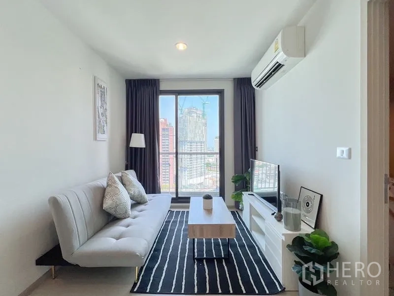 Condominium for rent or sale in Khlong Toei, Bangkok - Living room with floor-to-ceiling window and city skyline view.