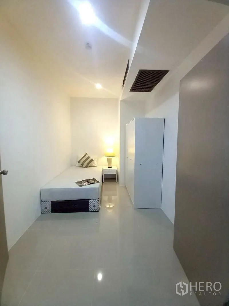 Condominium for rent in Watthana, Bangkok - Compact second bedroom with single bed, wardrobe and bedside lamp.