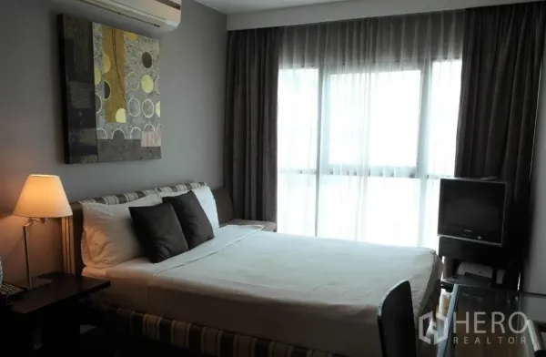 Condominium for rent or sale in Sathon, Bangkok - Cozy second bedroom with bed, desk, air conditioner and sheer‑draped windows.