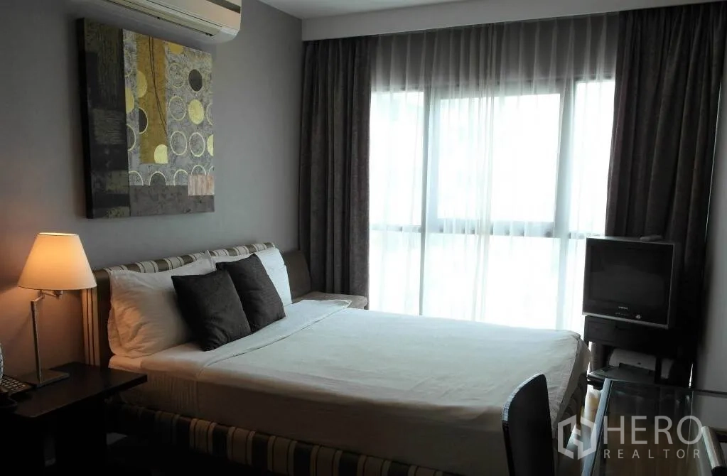 Condominium for rent or sale in Sathon, Bangkok - Cozy second bedroom with bed, desk, air conditioner and sheer‑draped windows.