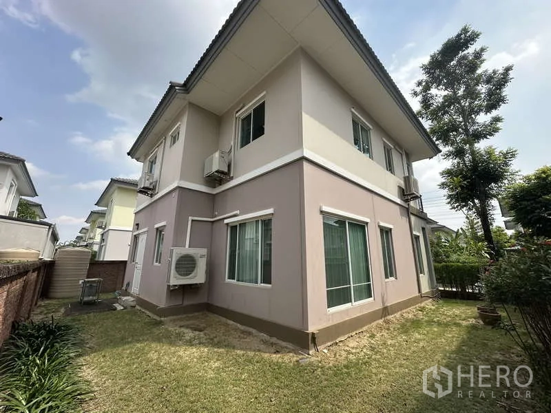 Detached House for sale in Sai Mai, Bangkok - Rear corner of the house with lawn, windows and external AC units.