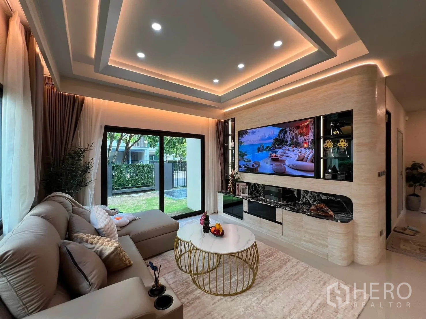 บ้านเดี่ยว for rent in Bang Phli, Samut Prakan - ห้องนั่งเล่นพร้อมโซฟา ผนังทีวี และประตูกระจกบานเลื่อนออกสู่สนามหญ้า.