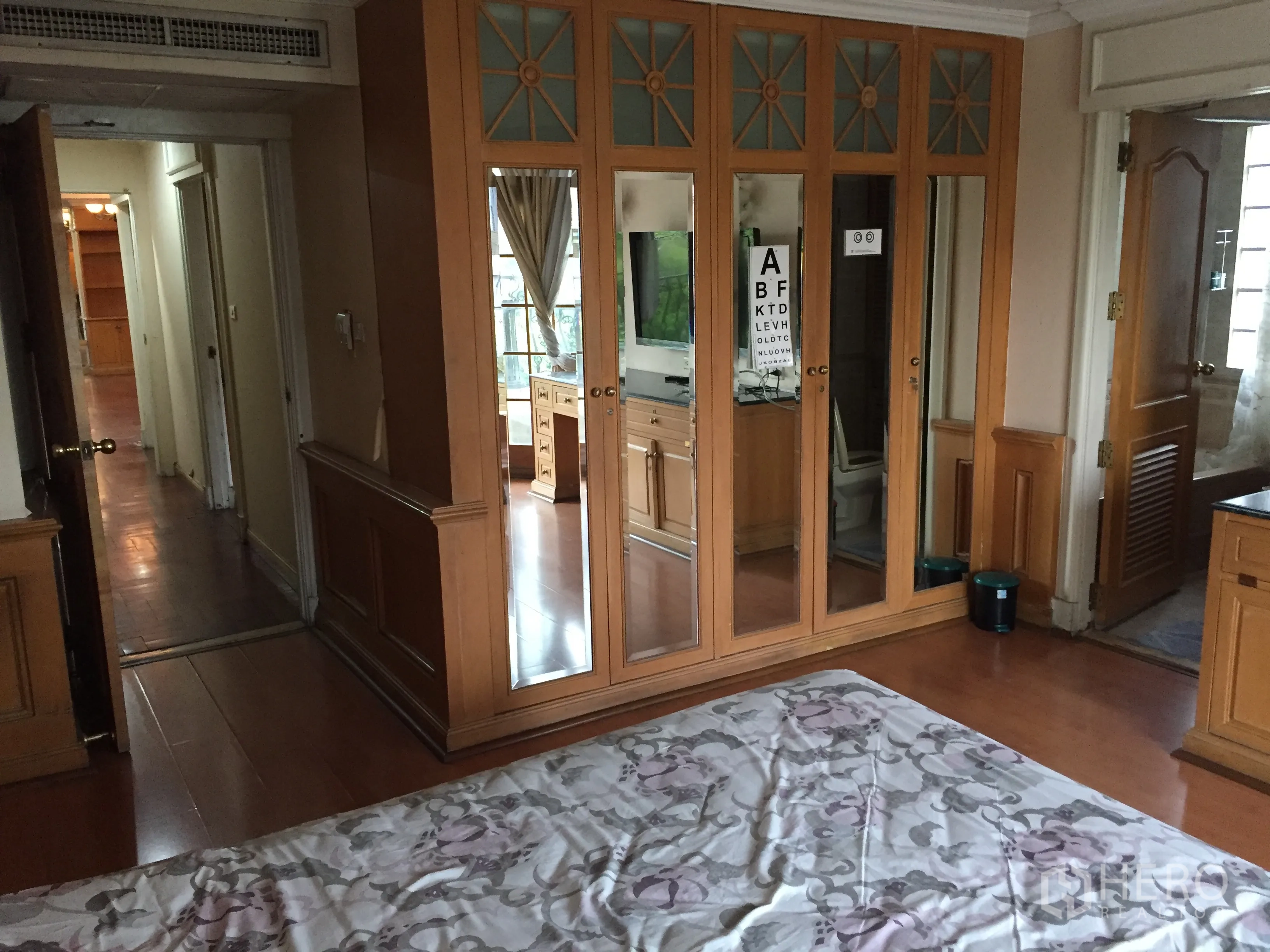 Condominium for rent in Khlong Toei, Bangkok - Built-in mirrored wardrobes with hallway view and doors to an en-suite bathroom.