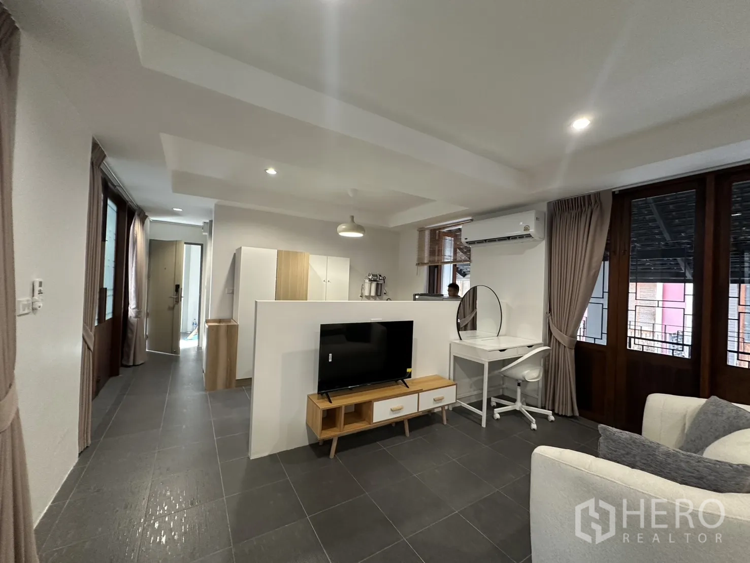 公寓 for rent in Pathum Wan, Bangkok - 开放式起居区，配电视柜、沙发、书桌与大窗。