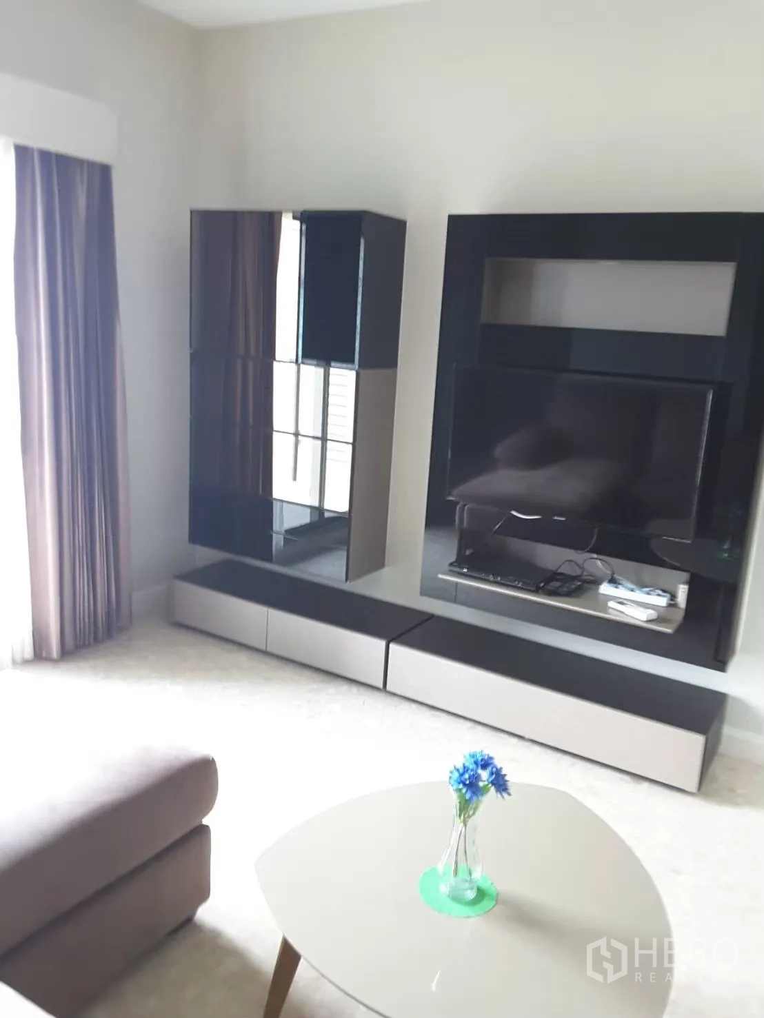 Condominium for rent in Khlong Toei, Bangkok - Living room with glossy black media wall, TV, and a small coffee table.