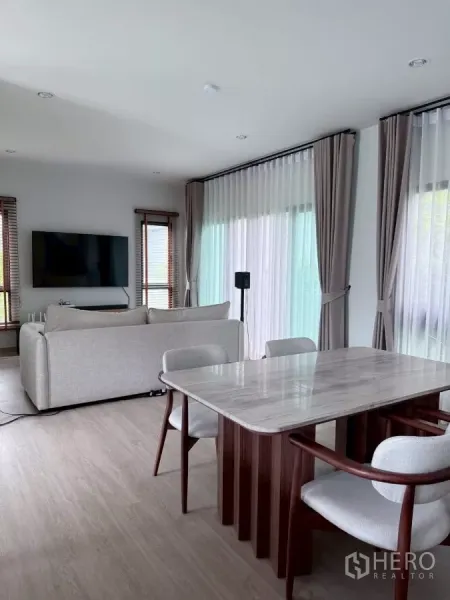 Detached House for rent in Lat Krabang, Bangkok - Open-plan living and dining area with marble-top table and floor-to-ceiling windows.