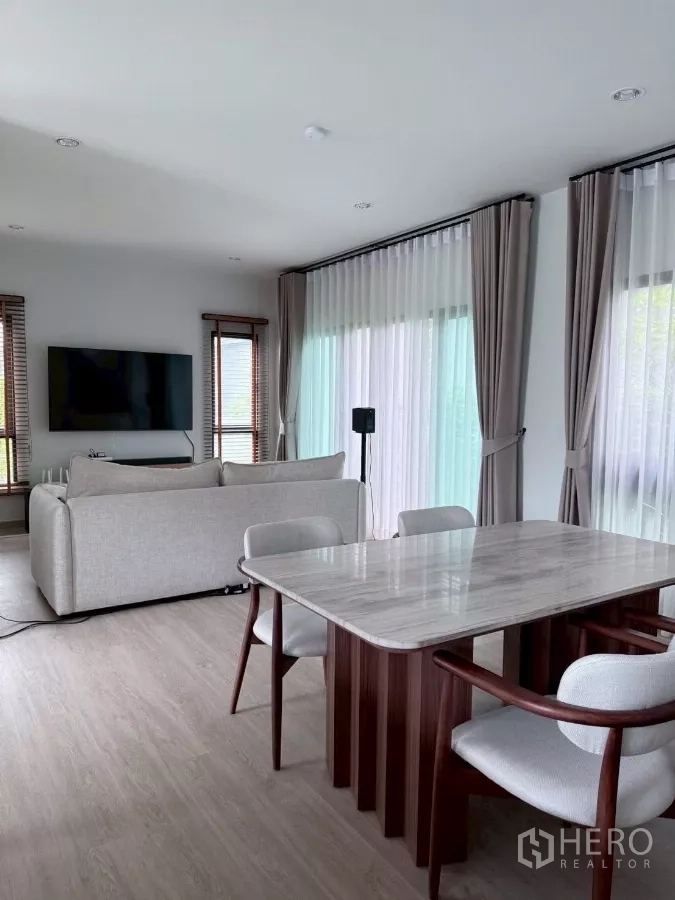 Detached House for rent in Lat Krabang, Bangkok - Open-plan living and dining area with marble-top table and floor-to-ceiling windows.