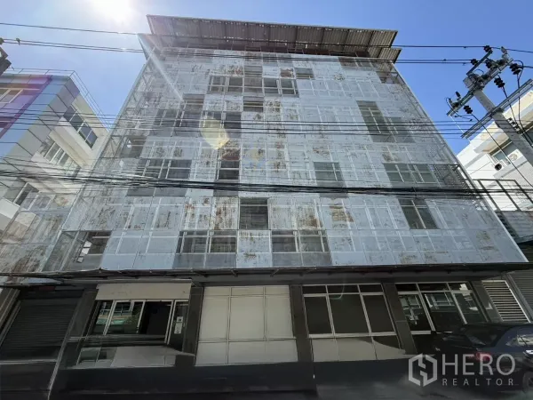 办公空间 出租在Bueng Kum, Bangkok - 五层办公楼正立面，穿孔金属外立面与停车区，阳光充足
