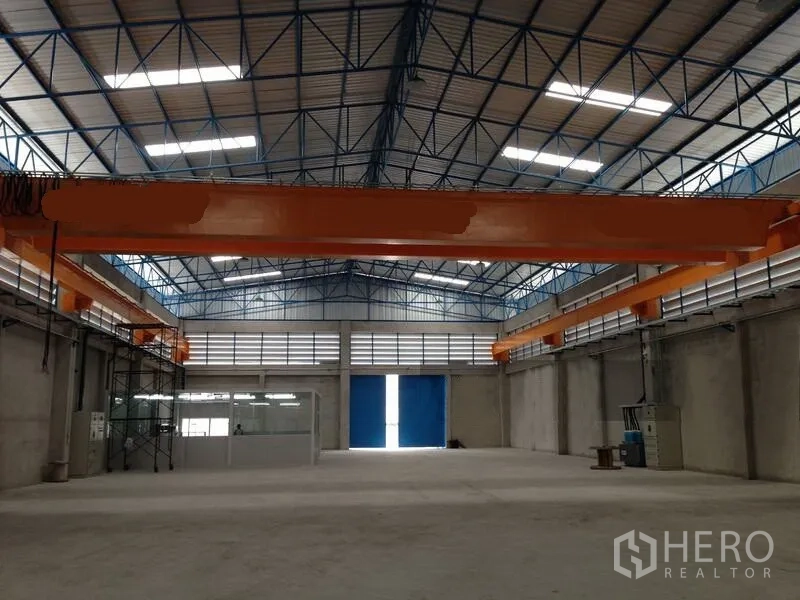 货栈 出租在Mueang Samut Prakan, Samut Prakan - 仓库中央视角，双侧起重机梁与高大的蓝色出入口。