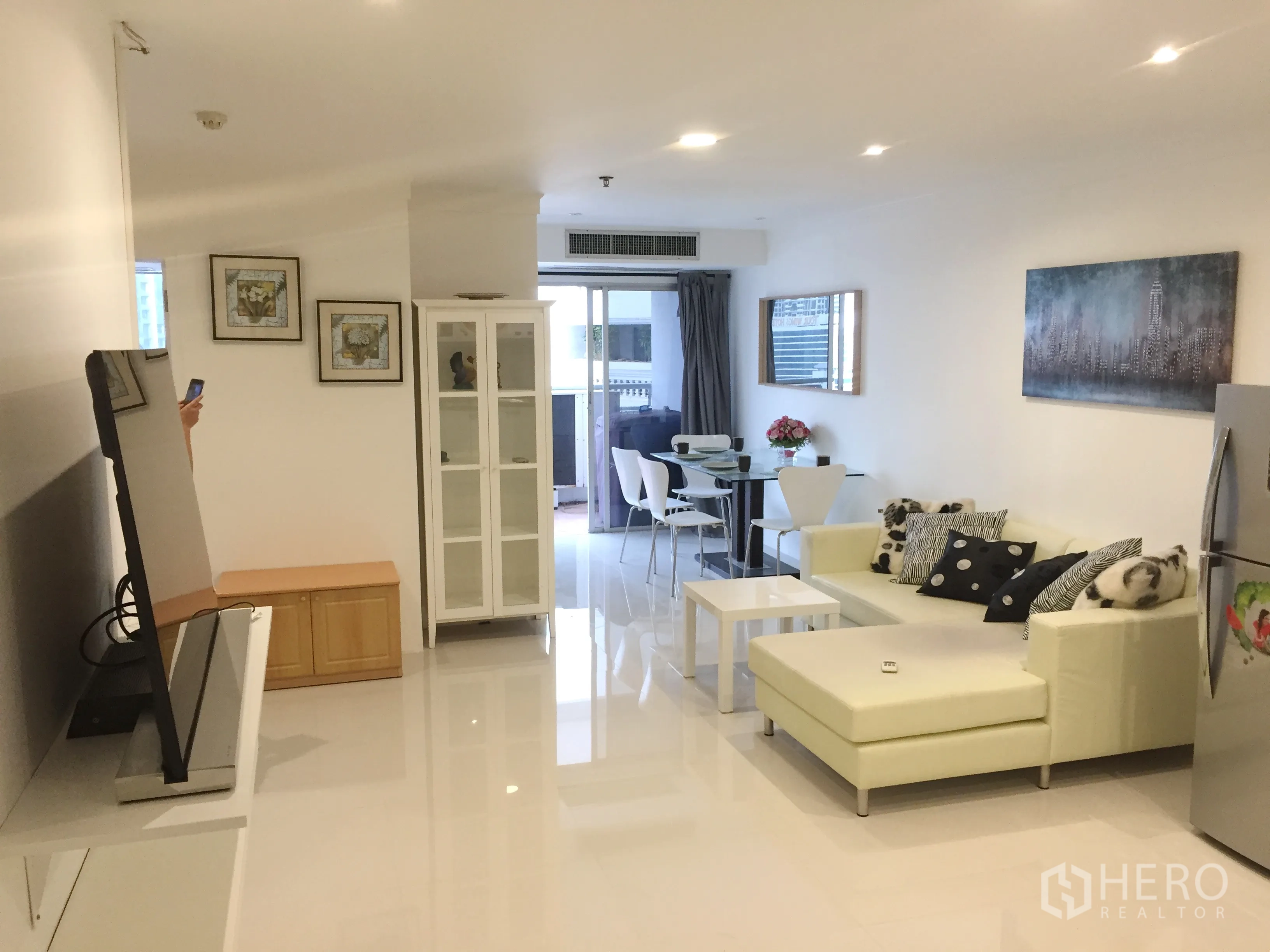 公寓 出售在Khlong Toei, Bangkok - 宽敞起居区，L形沙发、电视、展示柜，连通餐区与阳台。
