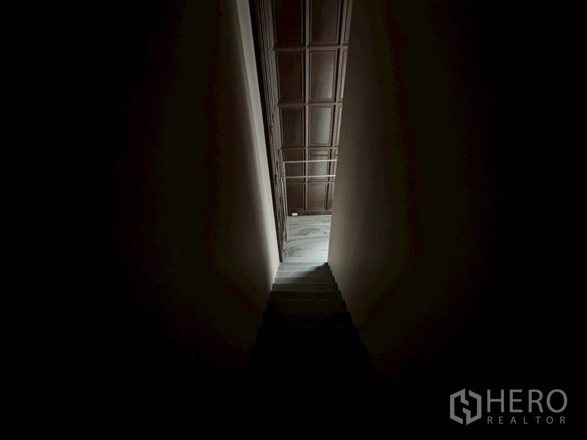 Condominium for sale in Bang Kho Laem, Bangkok - Dim stairwell descending toward the living space with a paneled wall ahead.