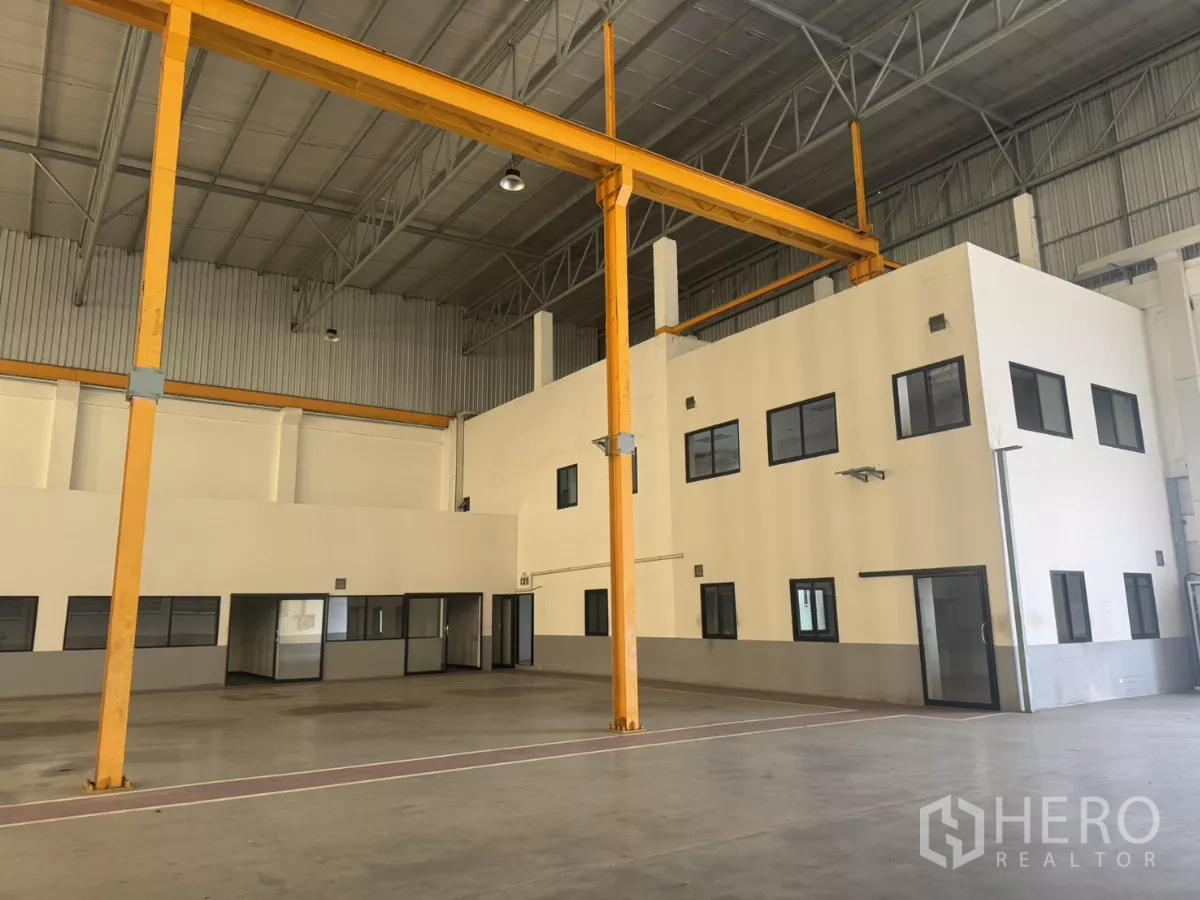 Factory for rent or sale in Bang Phli, Samut Prakan - High-ceiling factory floor with yellow overhead crane and two‑storey office block.