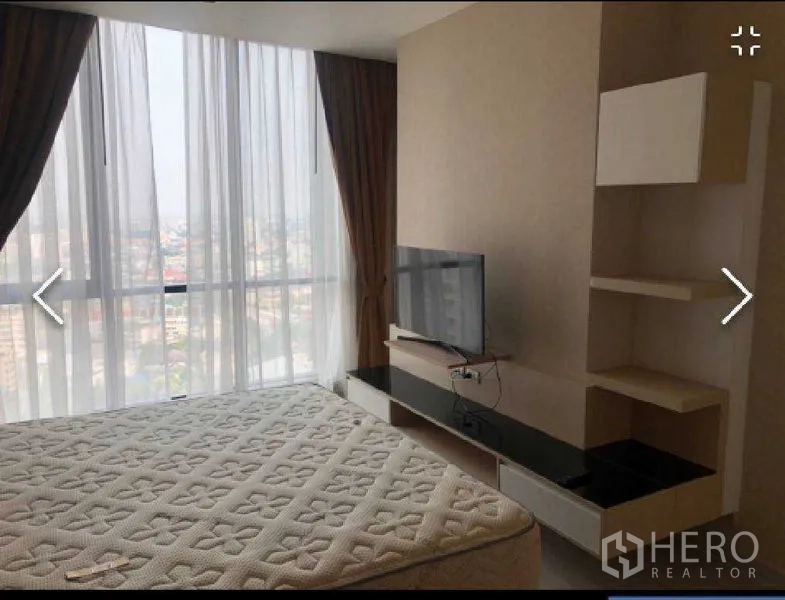 Condominium for rent in Watthana, Bangkok - Bedroom media wall with TV and shelving facing full-height windows and city view.