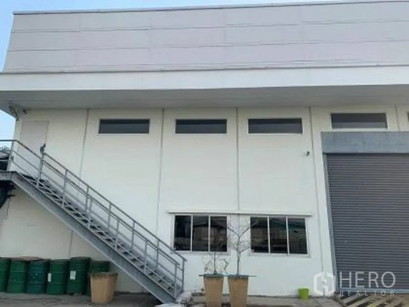 Factory for rent or sale in Wang Noi, Phra Nakhon Si Ayutthaya - Close-up façade showing windows, metal stairs and loading shutter.