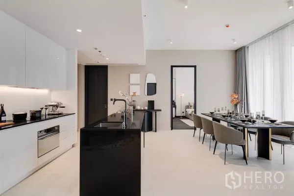 公寓 出租在Bang Rak, Bangkok - 现代厨房，黑色岛台与白色橱柜，旁设六人餐桌。