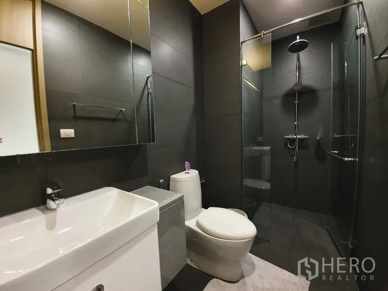 คอนโด ให้เช่าในPathum Wan, Bangkok - ห้องน้ำดีไซน์ทันสมัย พร้อมฝักบัวเรนชาวเวอร์และผนังกระเบื้องสีเข้ม