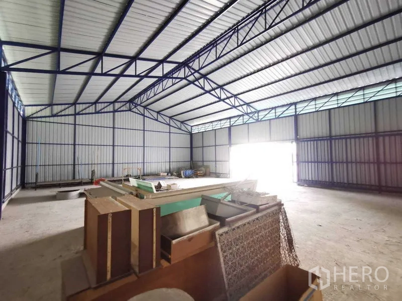 Warehouse for rent in Bang Na, Bangkok - Interior angle showing stored materials and view toward loading door