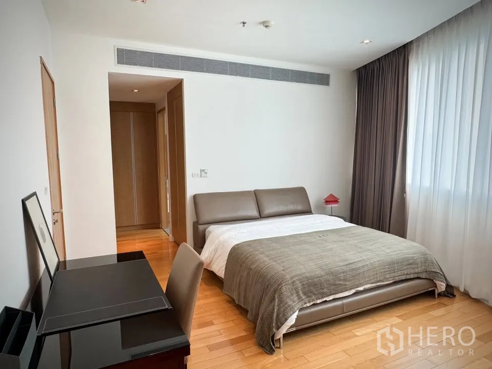 Condominium for rent or sale in Khlong Toei, Bangkok - Spacious bedroom featuring an upholstered bed, work desk, and wide windows with blackout curtains.