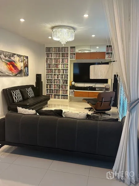 Detached House for sale in Saphan Sung, Bangkok - Media room with sofas, wall-mounted TV and built-in shelving for collections.