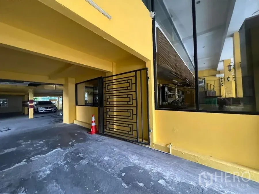零售空间 出租在Ratchathewi, Bangkok - 黄色商业建筑的有顶入口，配金属大门与大幅玻璃窗及车道出入