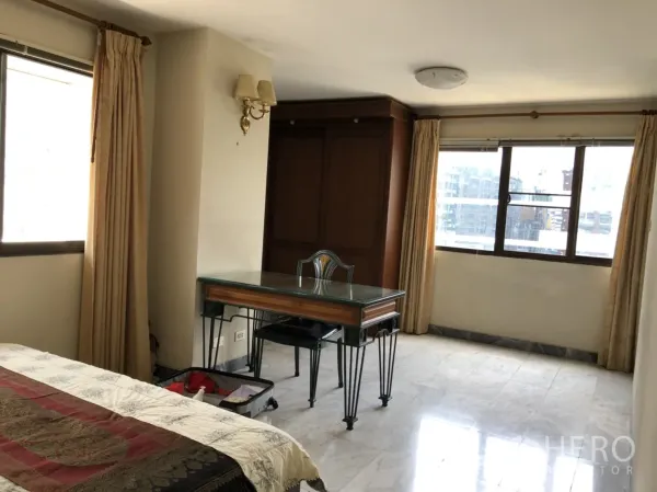 公寓 出租在Pathum Wan, Bangkok - 明亮卧室一角，玻璃台面书桌，石材地面与大窗户。