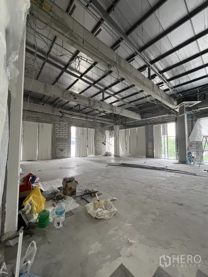 Retail Space for rent in Khlong Toei, Bangkok - Spacious open-plan shop area with exposed steel beams, hanging wiring and multiple window bays awaiting renovation.