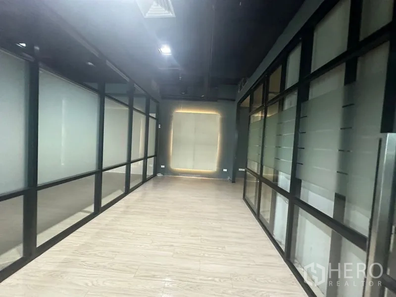 办公空间 出租在Bang Rak, Bangkok - 室内走道两侧为磨砂玻璃办公室，工业风深色天花。