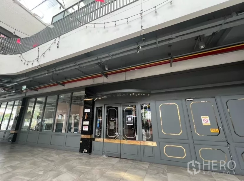 Retail Space for rent in Khlong Toei, Bangkok - Retail unit entrance with paneled doors beneath string lights in a mall.