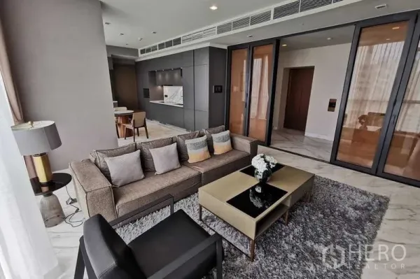 Condominium for rent or sale in Watthana, Bangkok - Bright living room with floor-to-ceiling windows, gray sofa and coffee table on a rug.