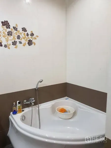 Townhouse for rent in Bang Kho Laem, Bangkok - Bathroom corner bathtub with handheld shower and floral tile accent.