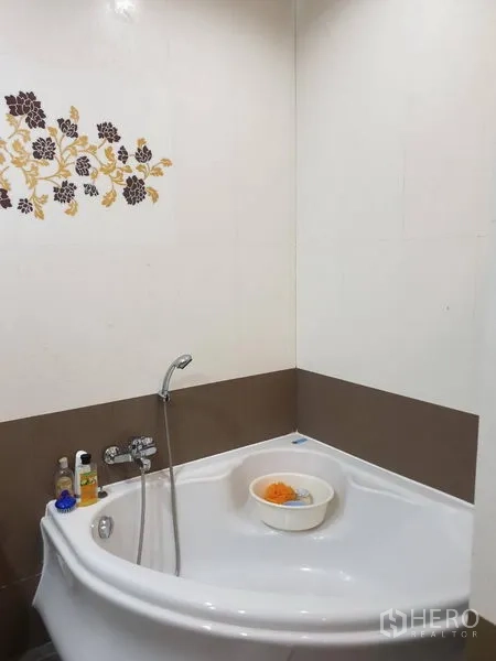 Townhouse for rent in Bang Kho Laem, Bangkok - Bathroom corner bathtub with handheld shower and floral tile accent.