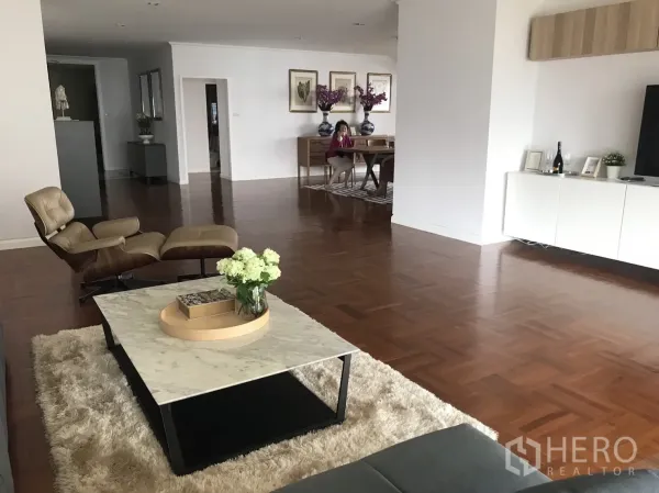Condominium for rent in Bangkok - Spacious living area with lounge chair, marble coffee table and warm wood floors.